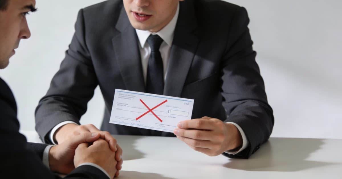 banquier examinant un cheque refuse devant client inquiet
