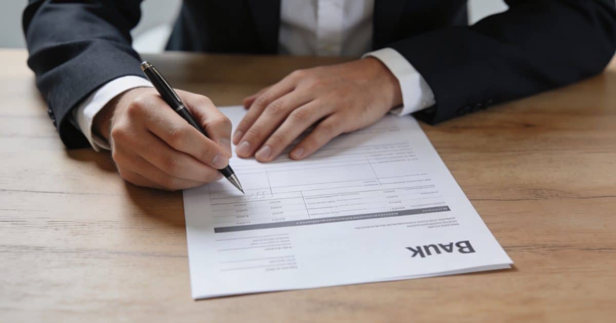 Client assis a un bureau remplissant formulaire bancaire