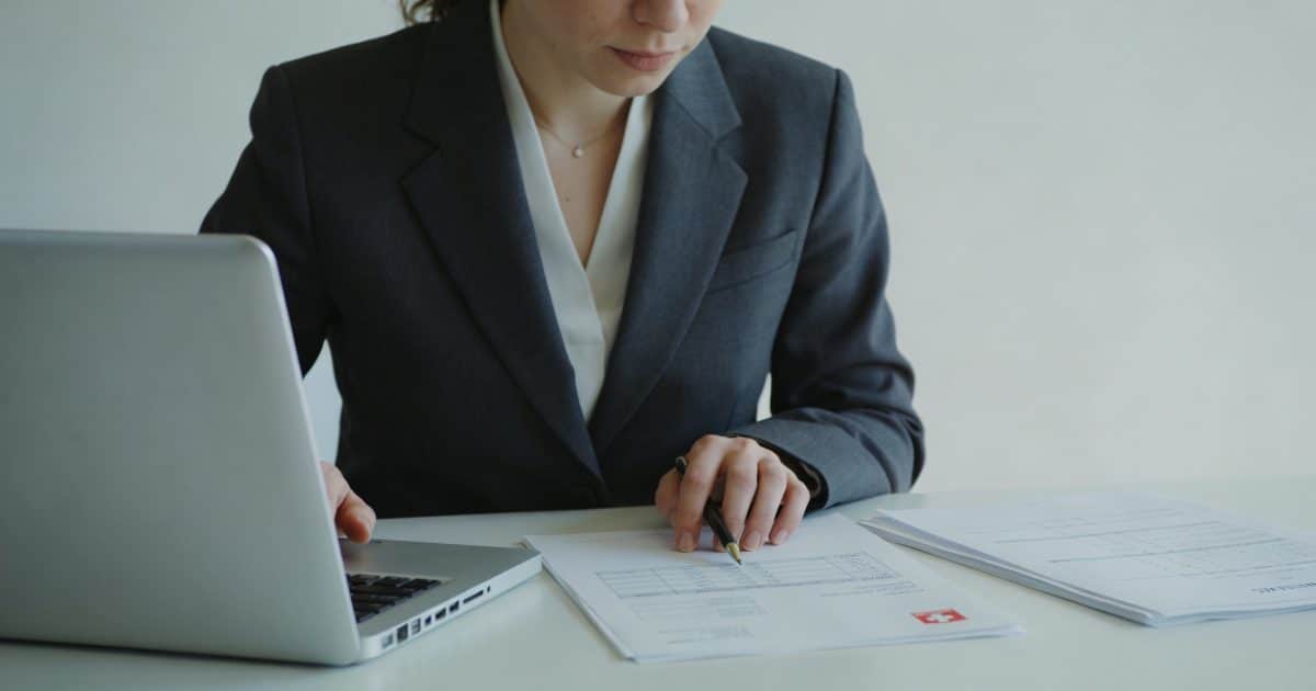 Femme en costume calcule des fiches de paie suisses