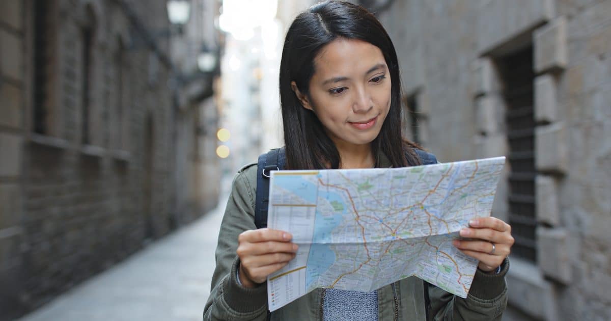 Jeune voyageuse consultant une carte devant ruelles sombres
