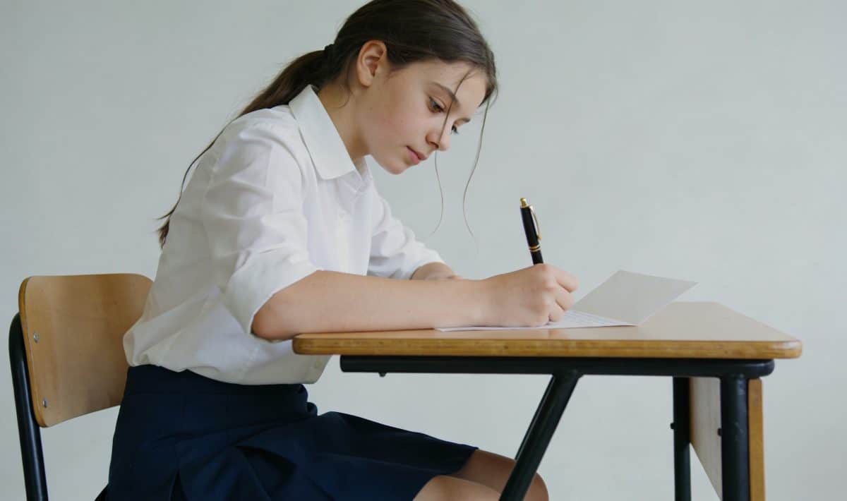 Lyceenne assise bureau ecrit lettre a la main