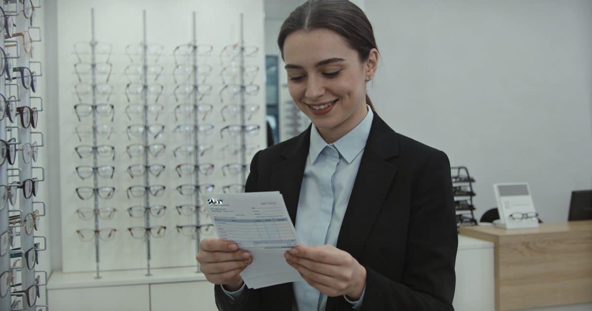 Opticien souriant debout en magasin regardant son salaire