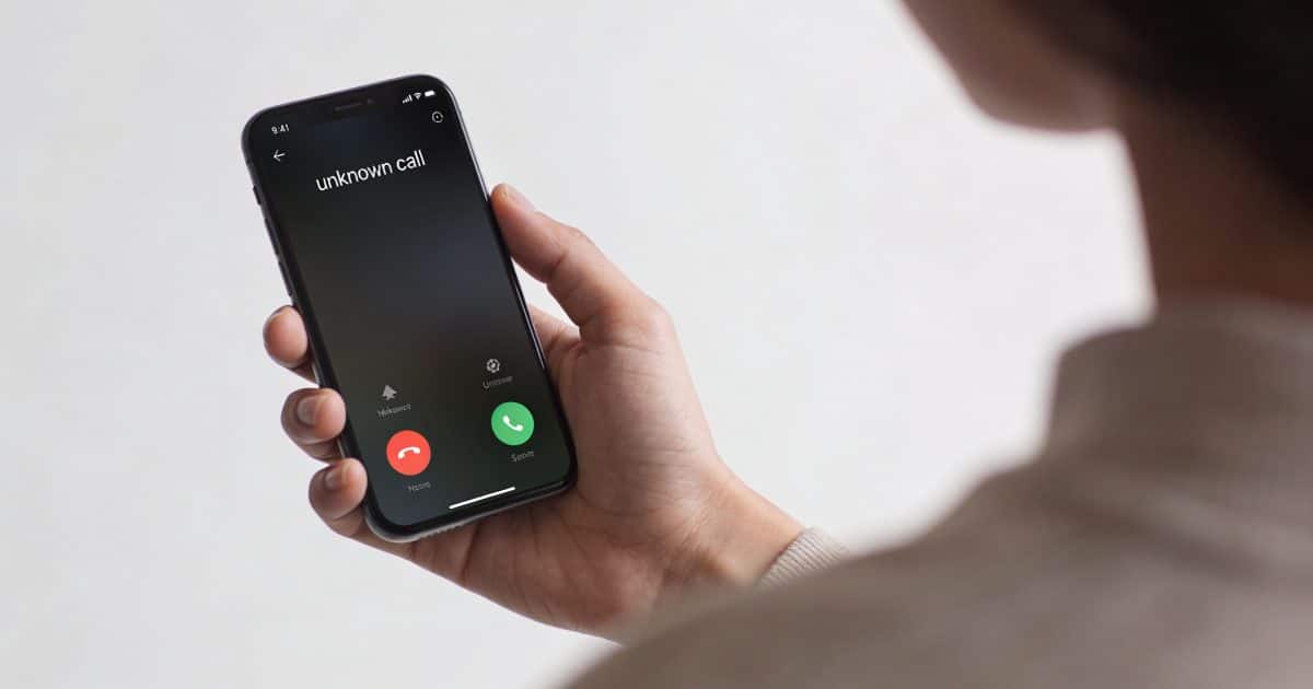 personne regarde ecran smartphone affichant appel inconnu