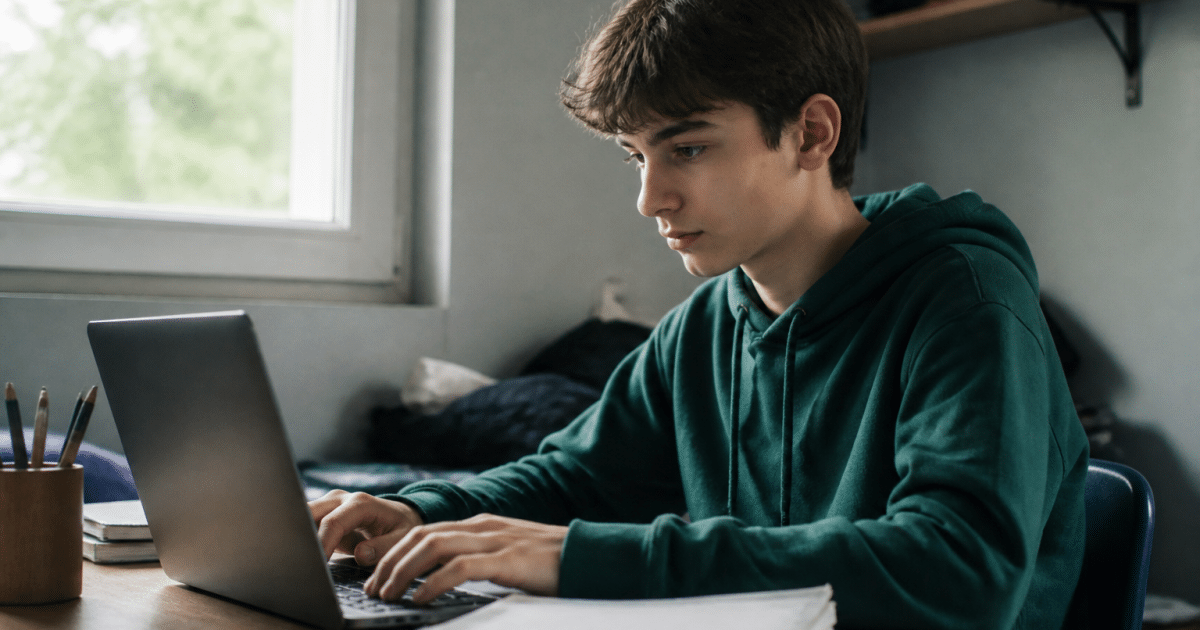 Adolescent assis au bureau face a ordinateur portable