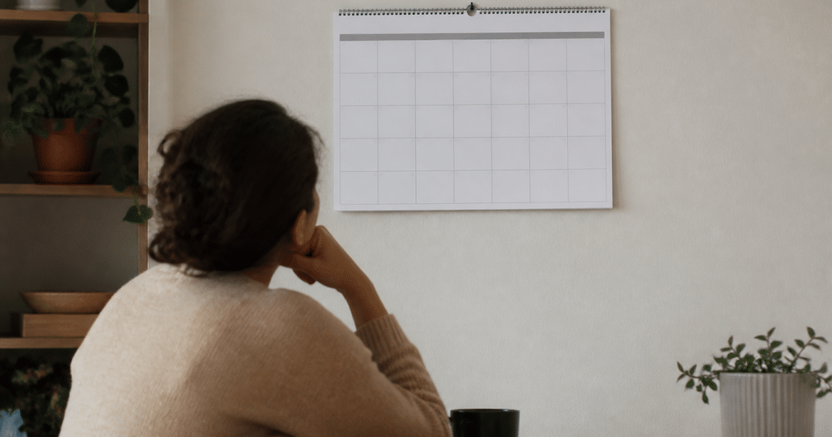 Personne assise regardant calendrier mural vide entre deux dates