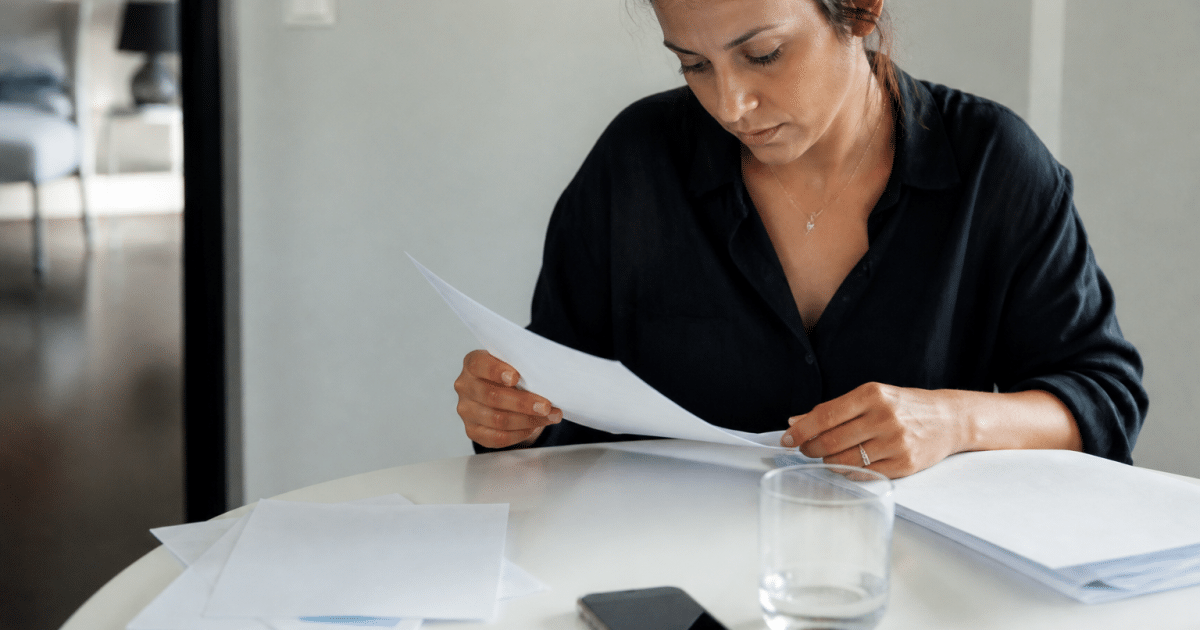 Femme consultant documents financiers sur table blanche