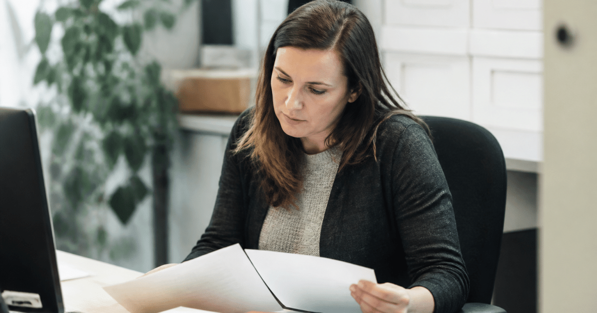 Personne assise a un bureau tenant des documents de formation professionnelle
