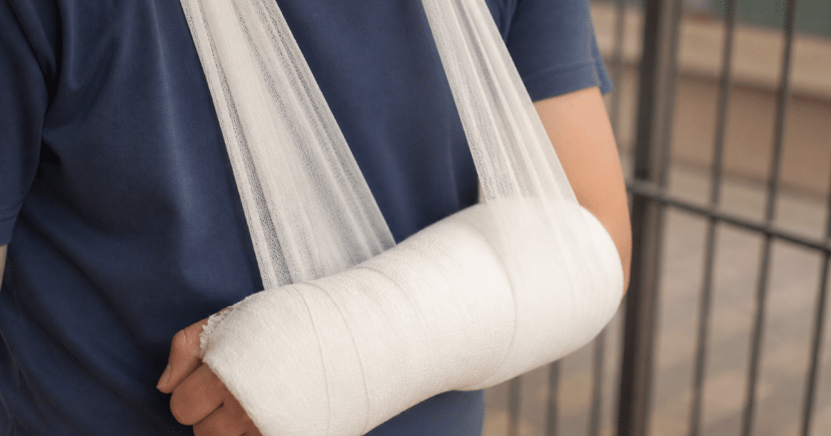 Gros plan sur un coude bandé, bras immobilisé en écharpe.