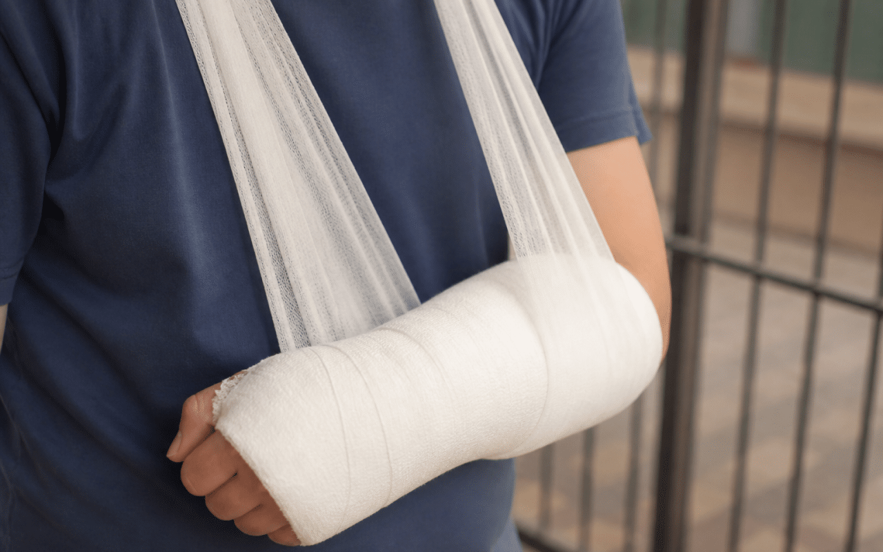 Gros plan sur un coude bandé, bras immobilisé en écharpe.