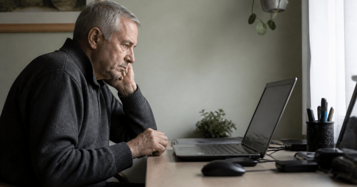 Homme age assis devant ordinateur consultant offres emploi.