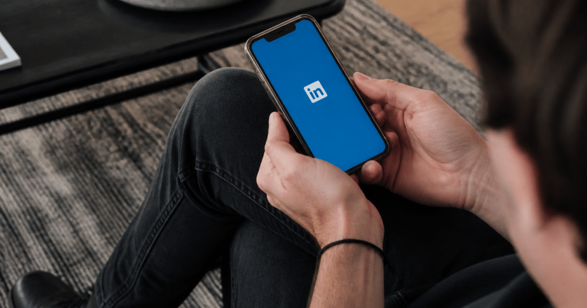 Personne consultant smartphone affichant logo LinkedIn sur ecran