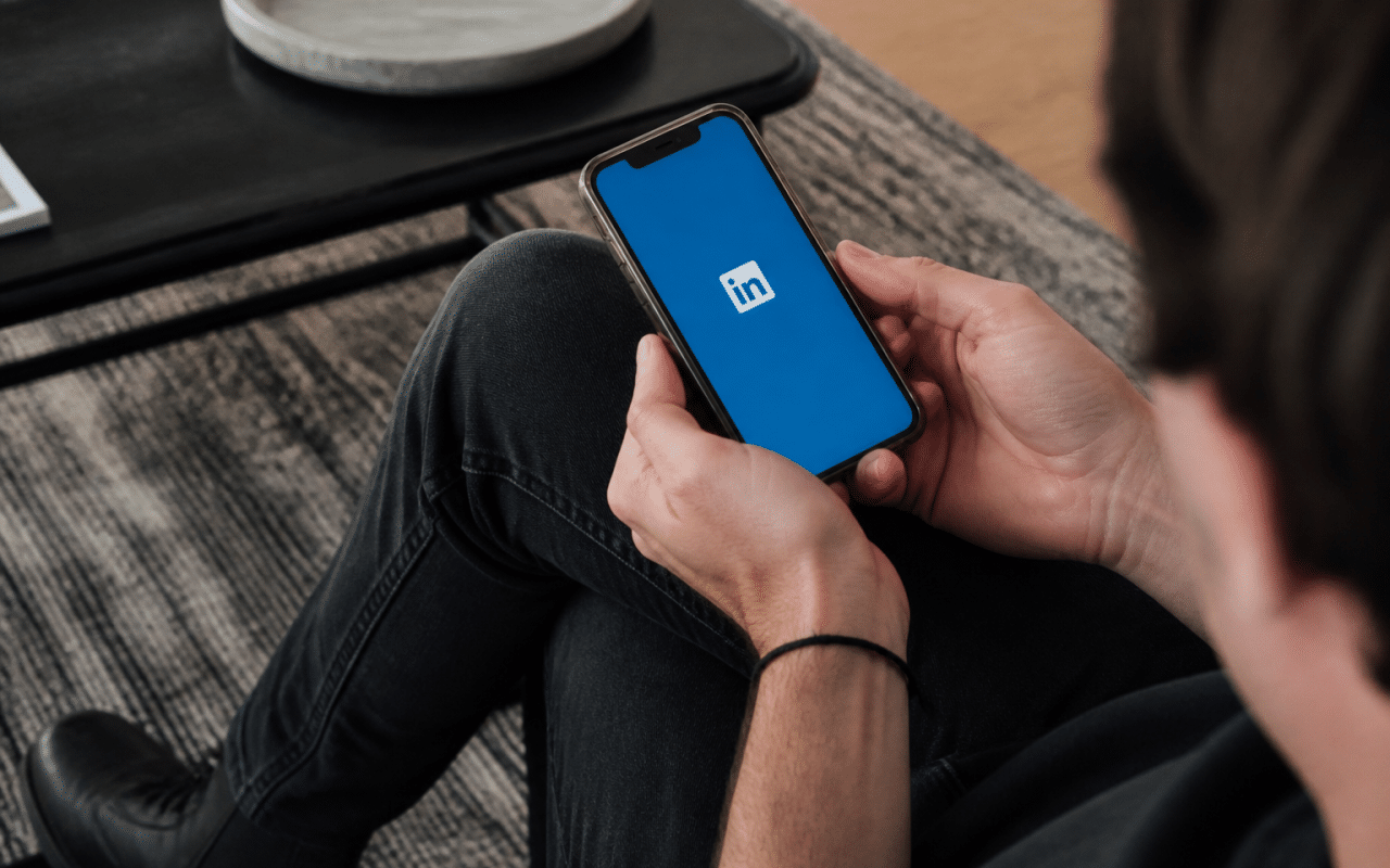 Personne consultant smartphone affichant logo LinkedIn sur ecran