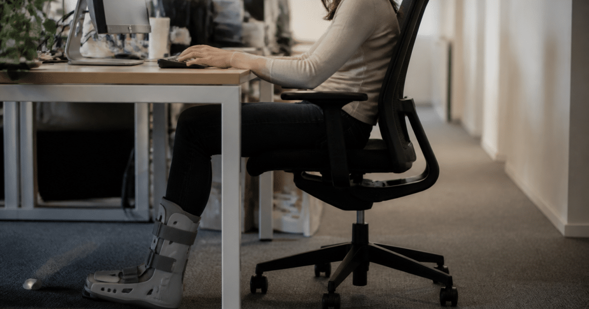 Personne assise au bureau portant une attelle au pied