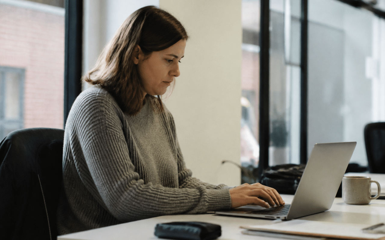 Personne assise au bureau travaillant sur ordinateur portable.