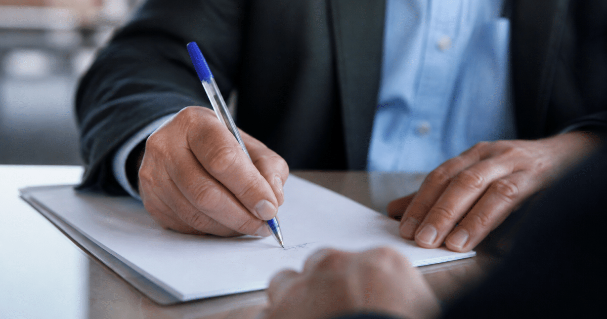 Personne signant document commercial avec stylo bleu.