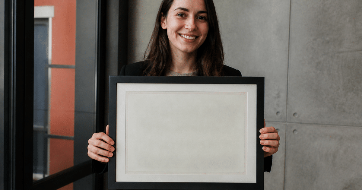 Personne tenant un parchemin diplome encadre devant elle