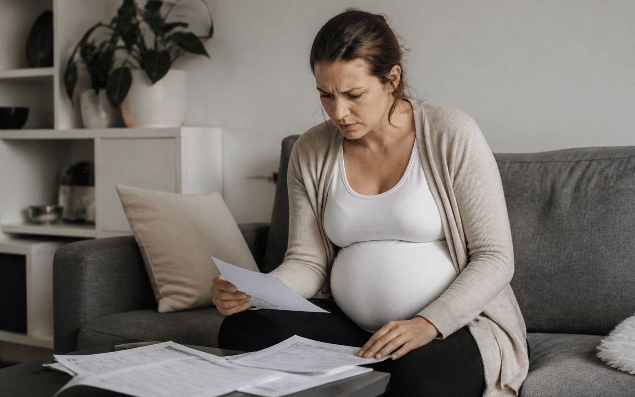 Femme enceinte tenant documents medicaux, mine preoccupee.