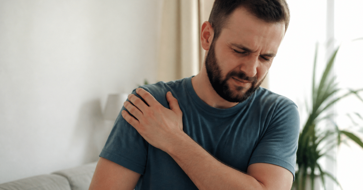 Personne tenant son epaule douloureuse avec la main gauche levee