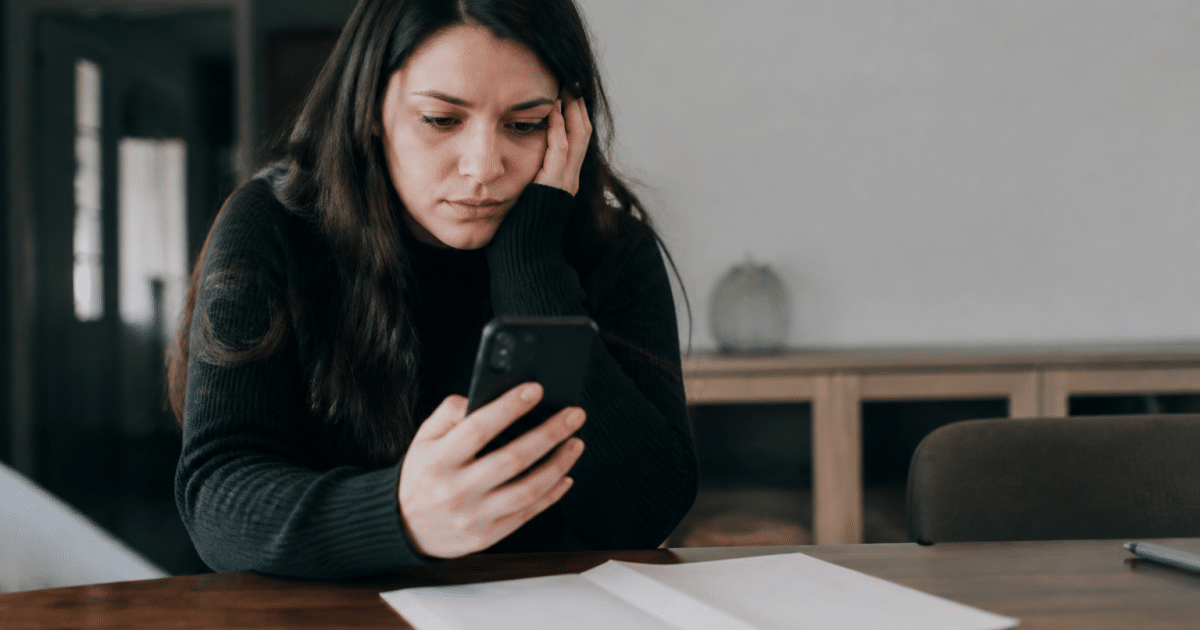 Personne consultant telephone avec relevé bancaire vide sur table