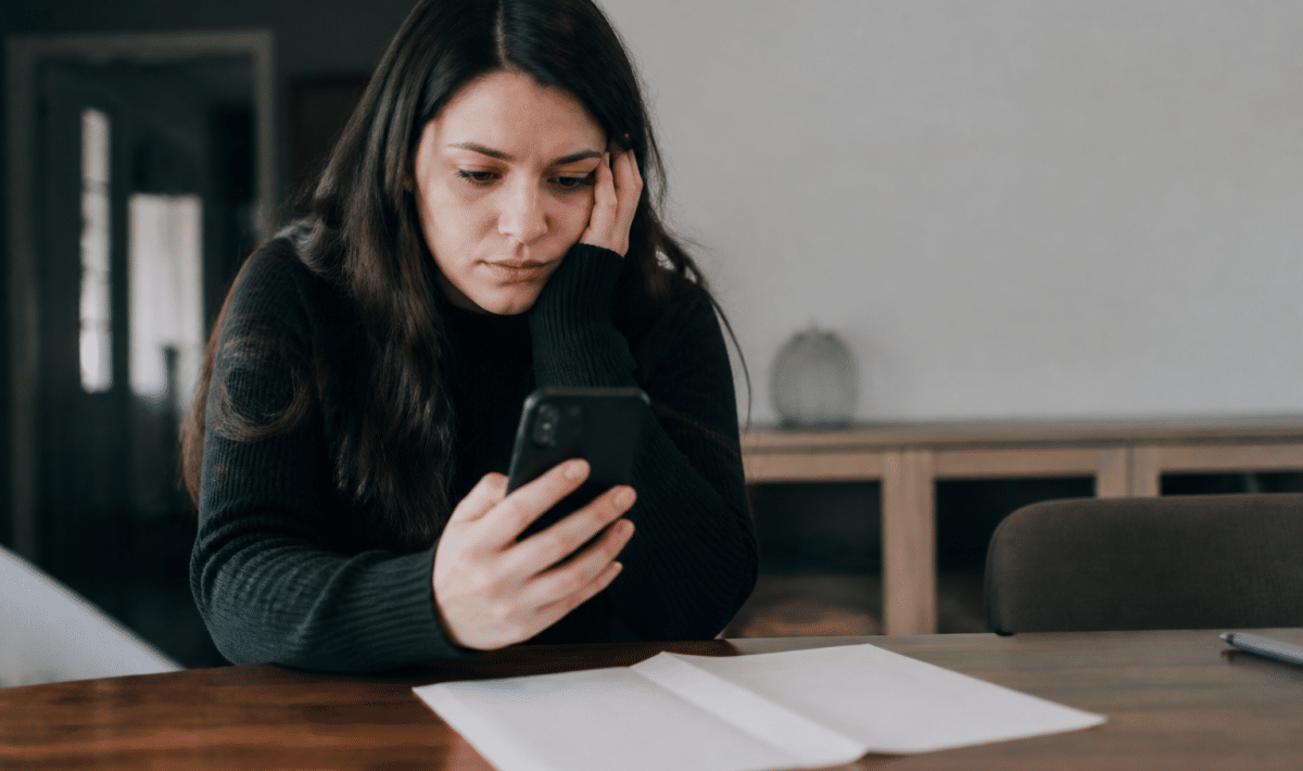 Personne consultant telephone avec relevé bancaire vide sur table
