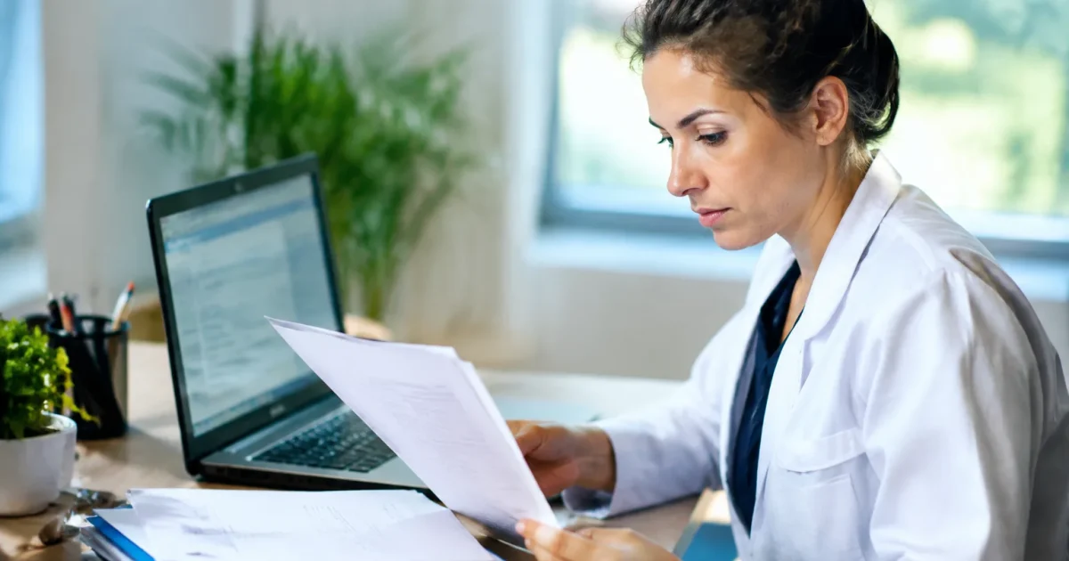 Personne assise devant ordinateur consultant documents administratifs médicaux