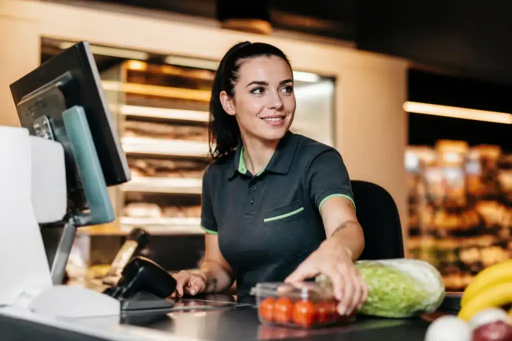 Caissiere en uniform derriere son comptoir de supermarche