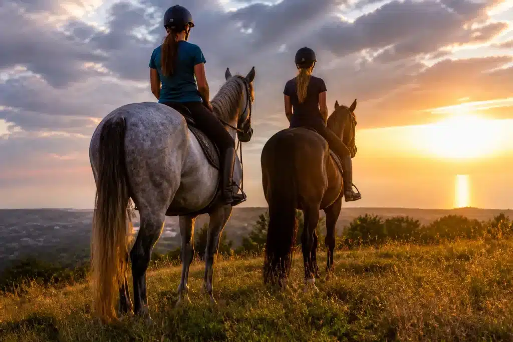 Cavaliers montant chevaux au coucher soleil estival