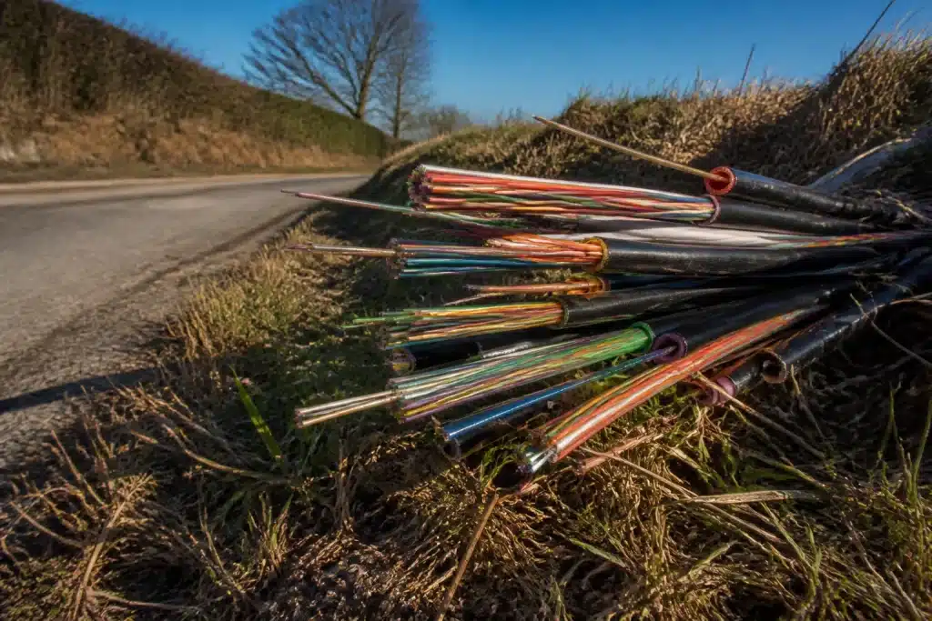 Cables de fibre optique arretes au bord d'une route rurale