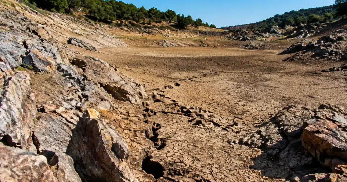 Bassin asseche avec berges rocheuses erodees et crevasses profondes visibles