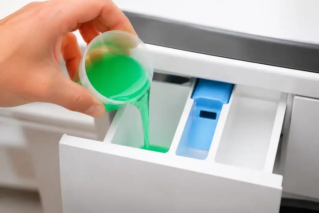 Liquide vert versé dans compartiment machine à laver