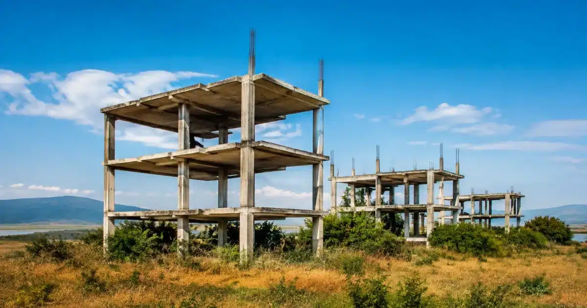 Structures beton inachevees s'elevent dans champ desert herbe