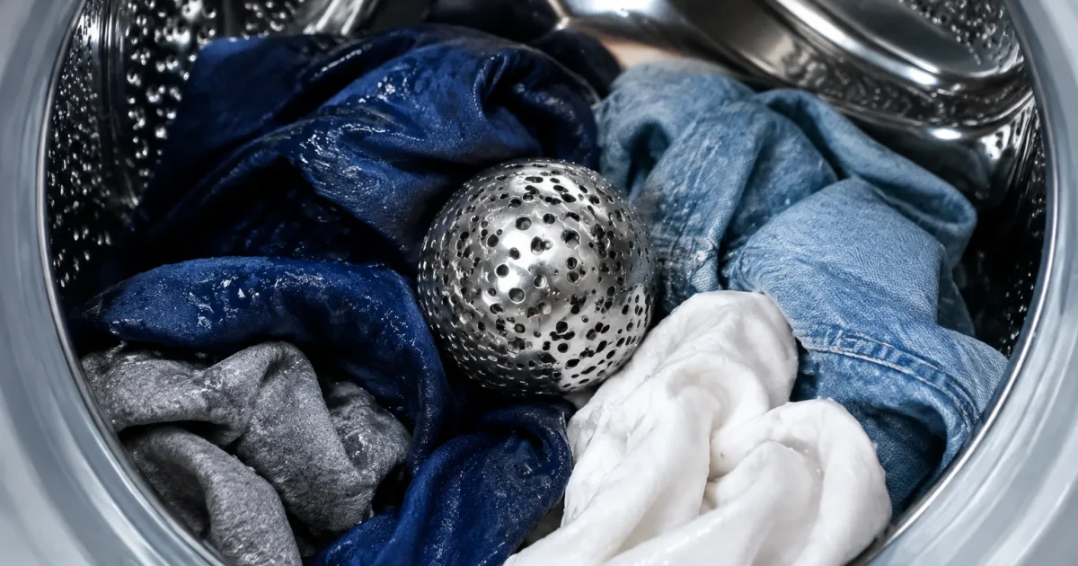 Sphere metallique argentee reposant dans tambour lave-linge avec vetements humides