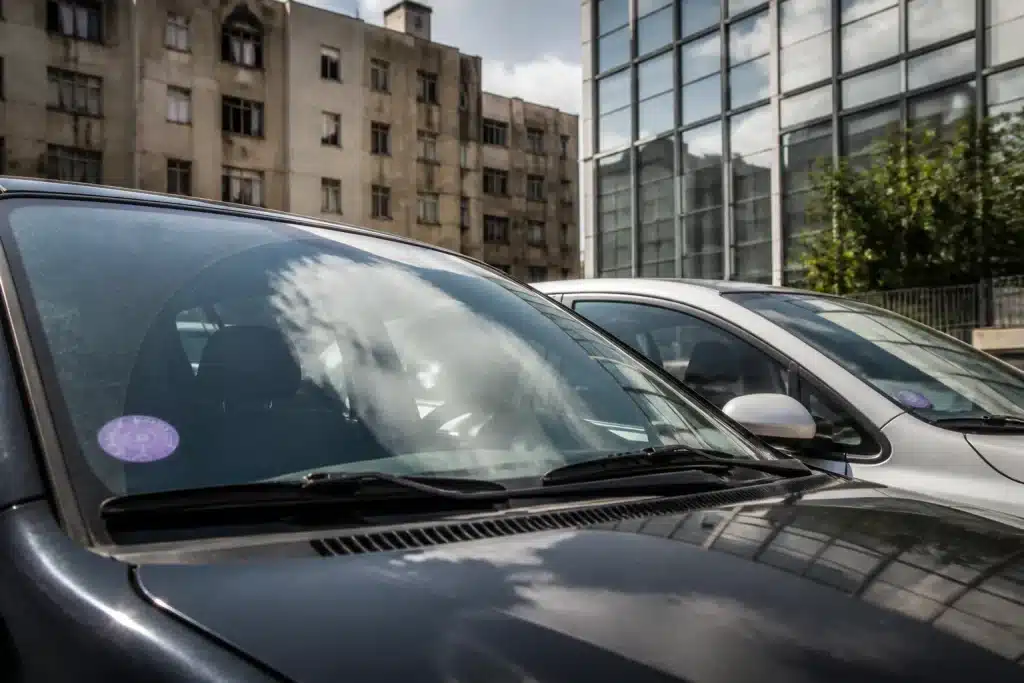 Deux voitures pare-brise, vignette Crit'Air visible, inégalité économique urbaine