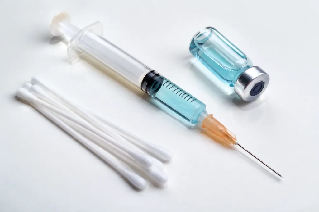 Seringue vaccin et ecouvillons medicaux sur surface blanche